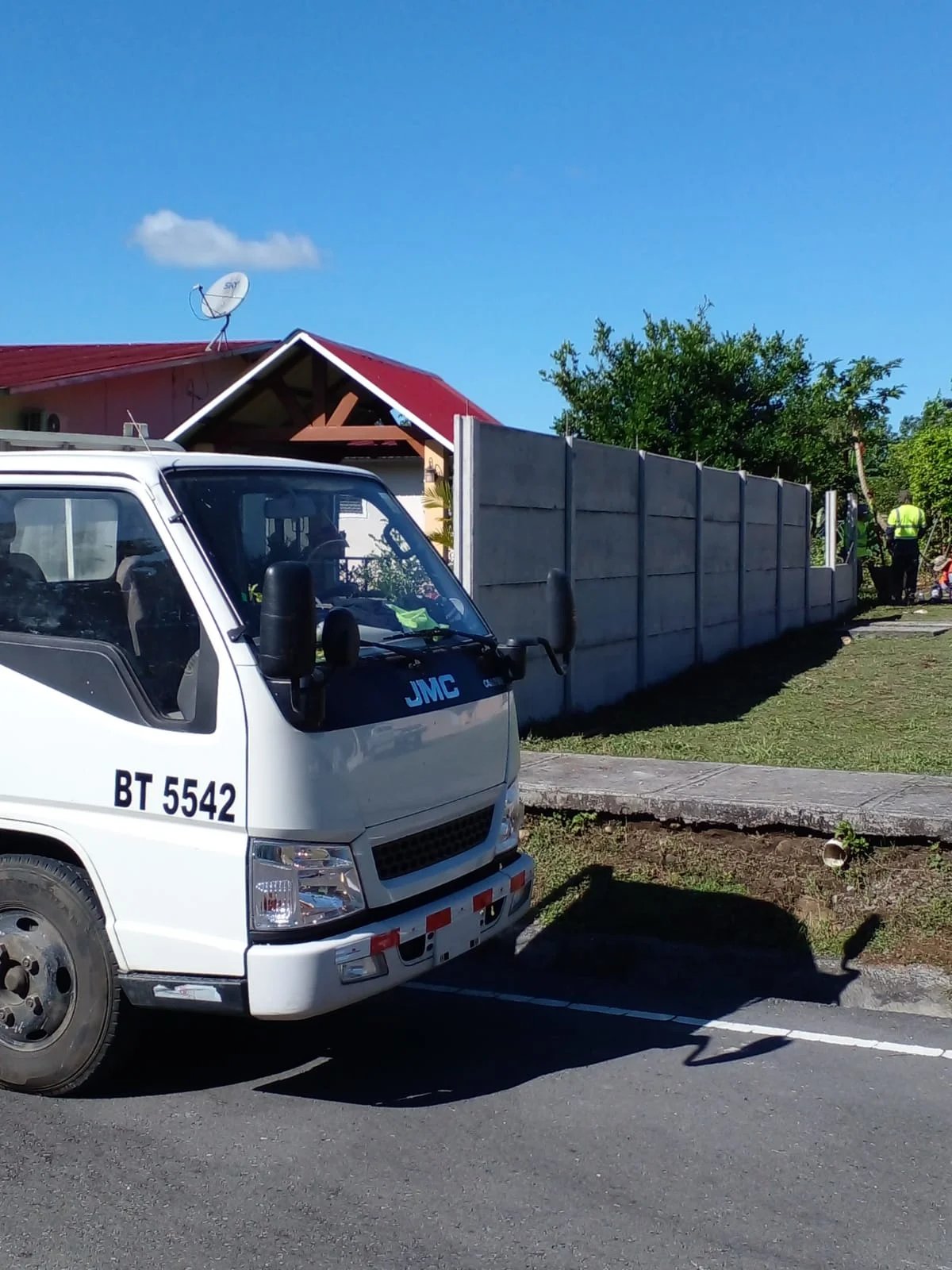 Camión de transporte junto a muro perimetral prefabricado recién instalado en zona residencial