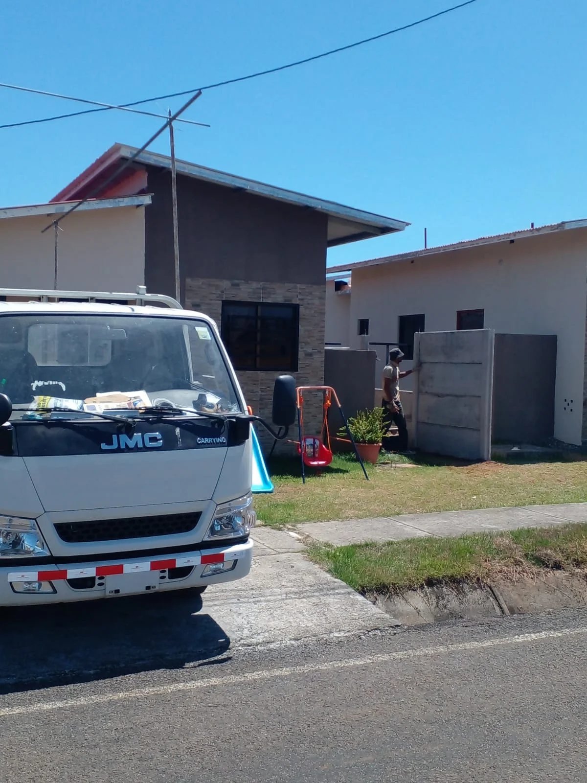 Camión de obra estacionado junto a muro perimetral prefabricado en residencia con techo de teja