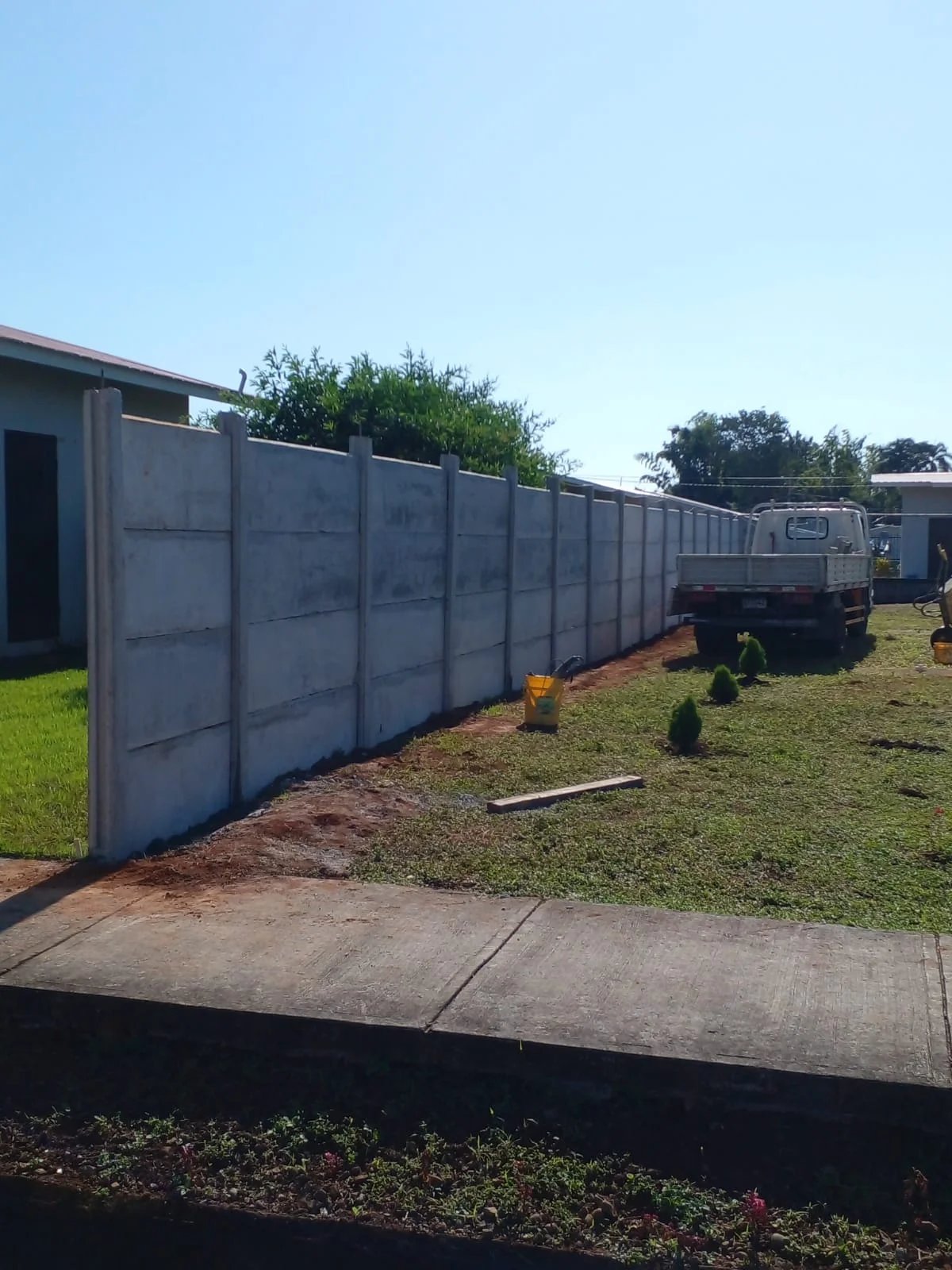 Muro perimetral prefabricado terminado con camión de la cuadrilla estacionado al fondo