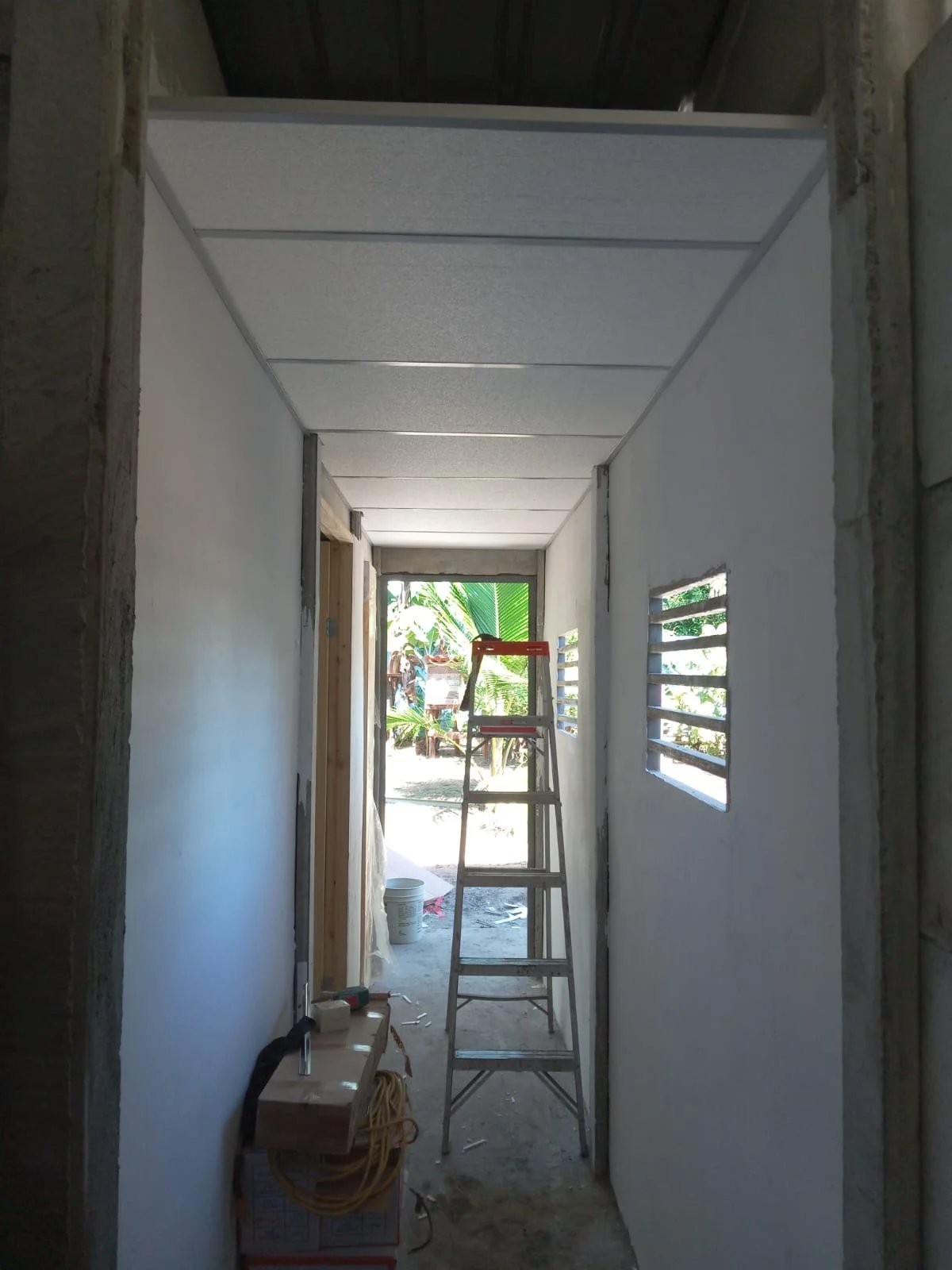 Vista interior de anexo con cielo raso de PVC blanco y escalera en proceso de terminación