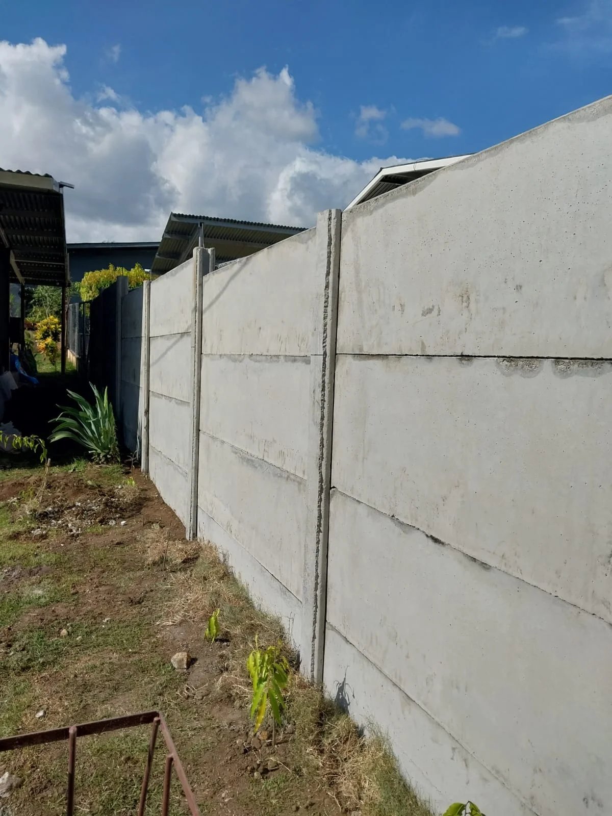 Muro perimetral prefabricado terminado entre dos residencias con jardín delantero