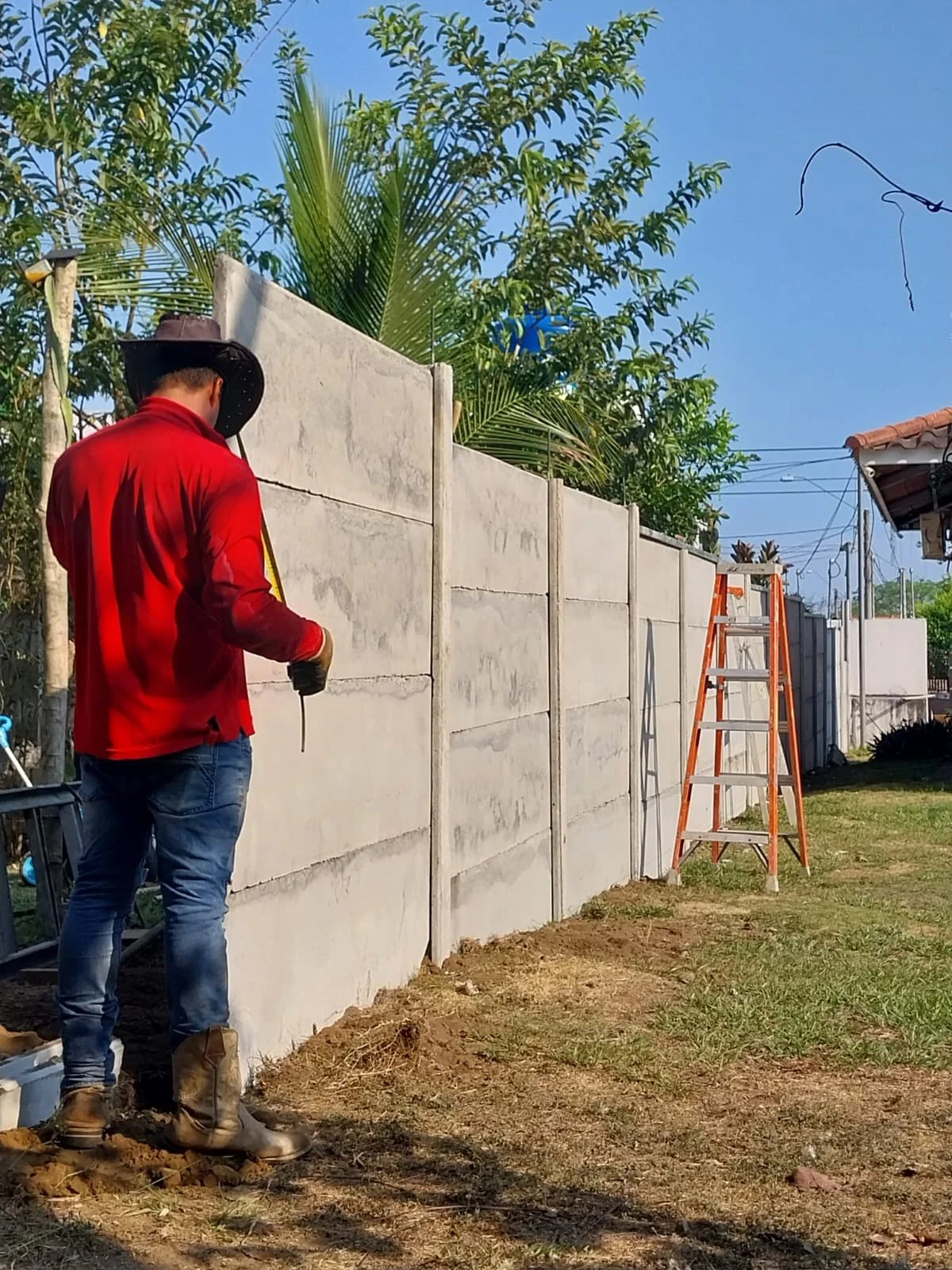 Operario con sombrero taladrando muro perimetral prefabricado durante terminación de obra