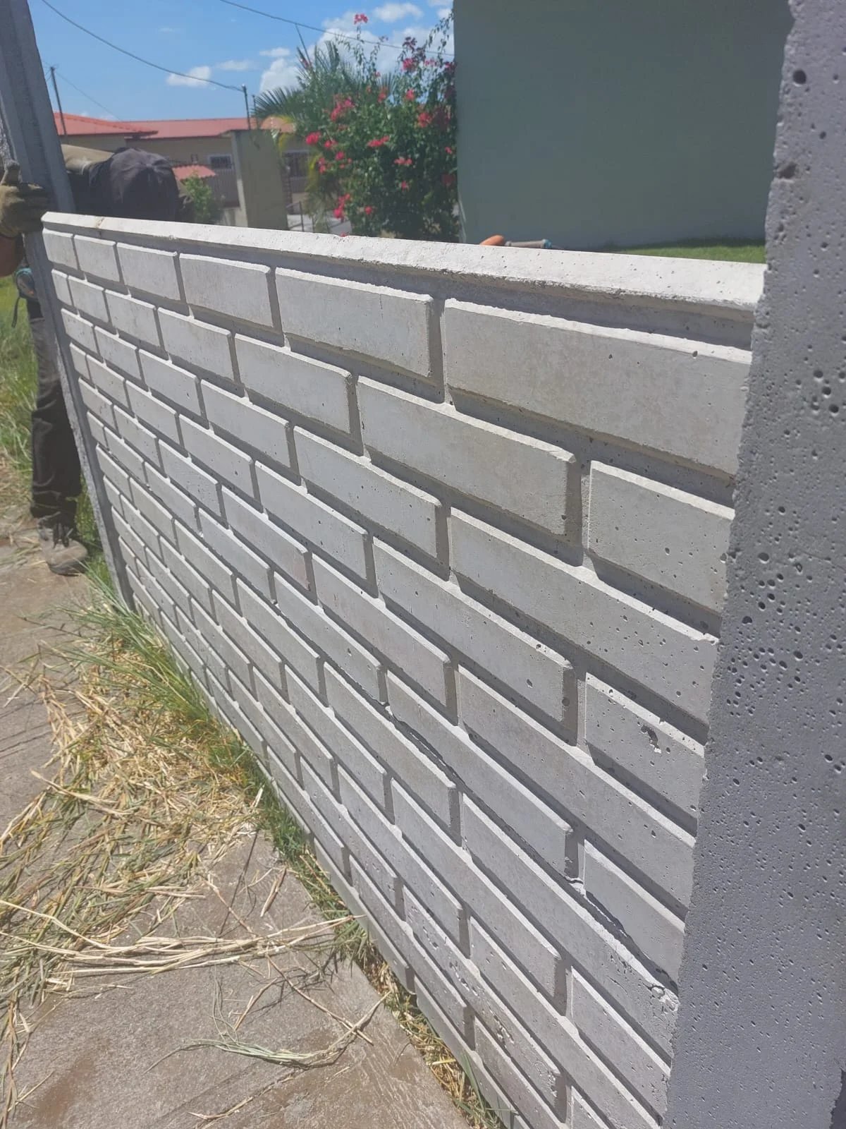 Detalle de muro prefabricado con textura tipo ladrillo en residencia con jardín al fondo