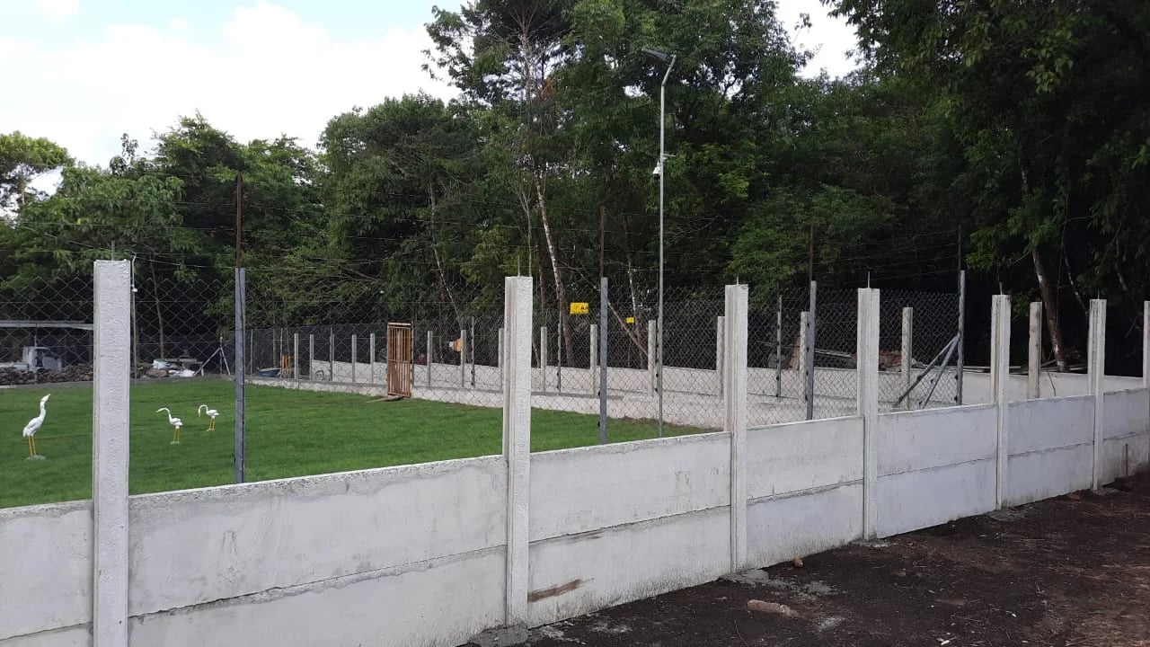 Muro perimetral prefabricado bajo con cerca de alambre superior en finca con gallinas