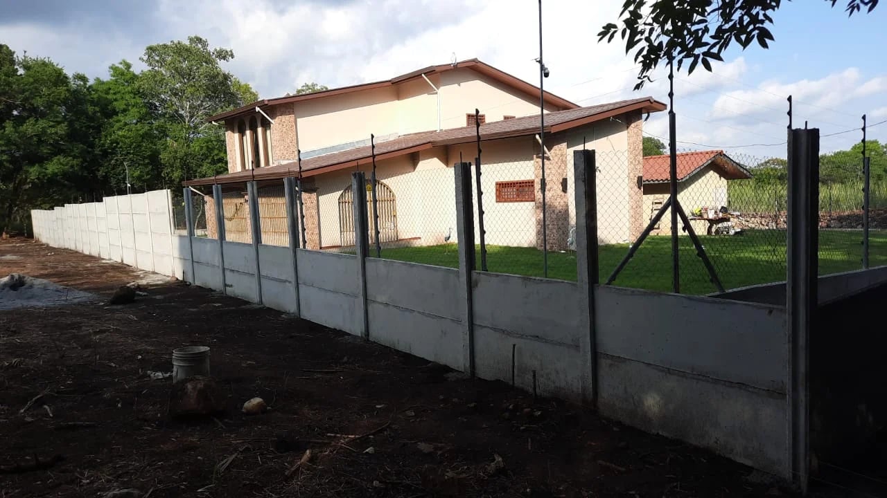 Residencia tipo finca con muro perimetral prefabricado alto y cerca de alambre como refuerzo