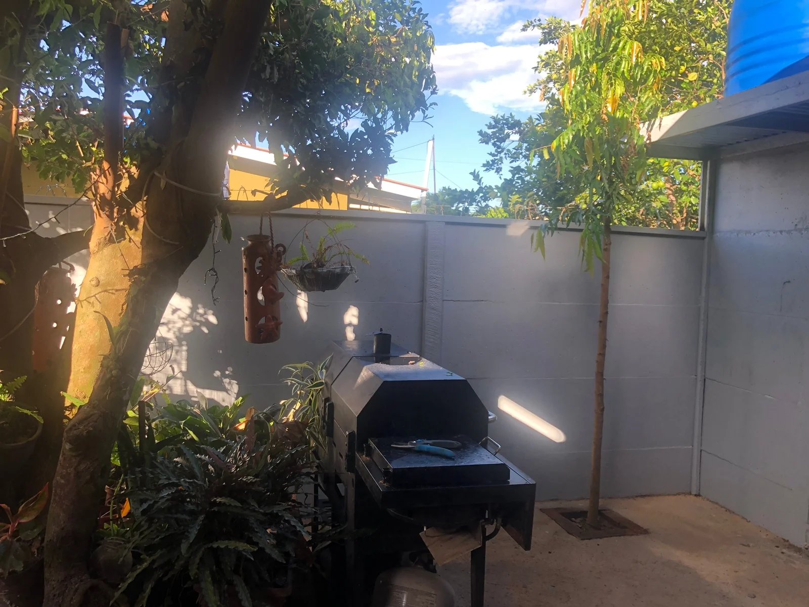 Muro perimetral prefabricado pintado integrado en patio trasero con parrilla y vegetación