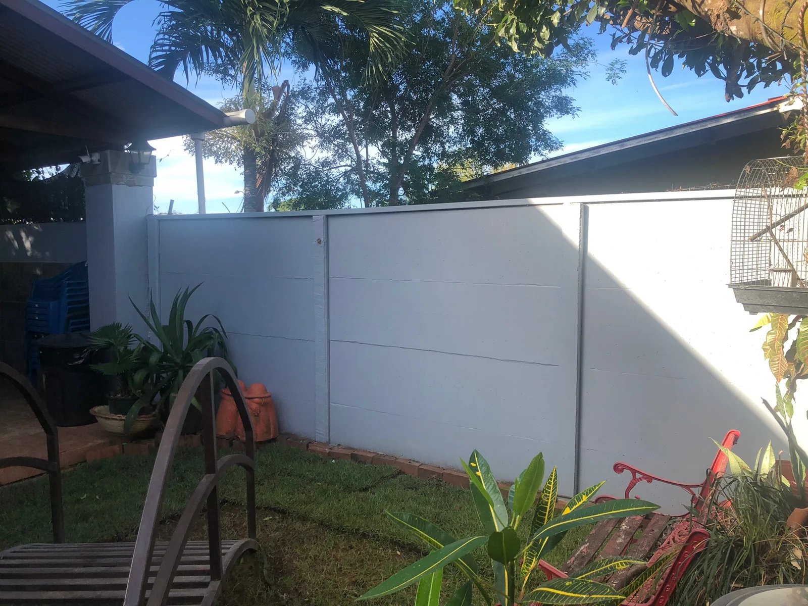 Muro perimetral prefabricado pintado de blanco en residencia con jardín y mobiliario exterior