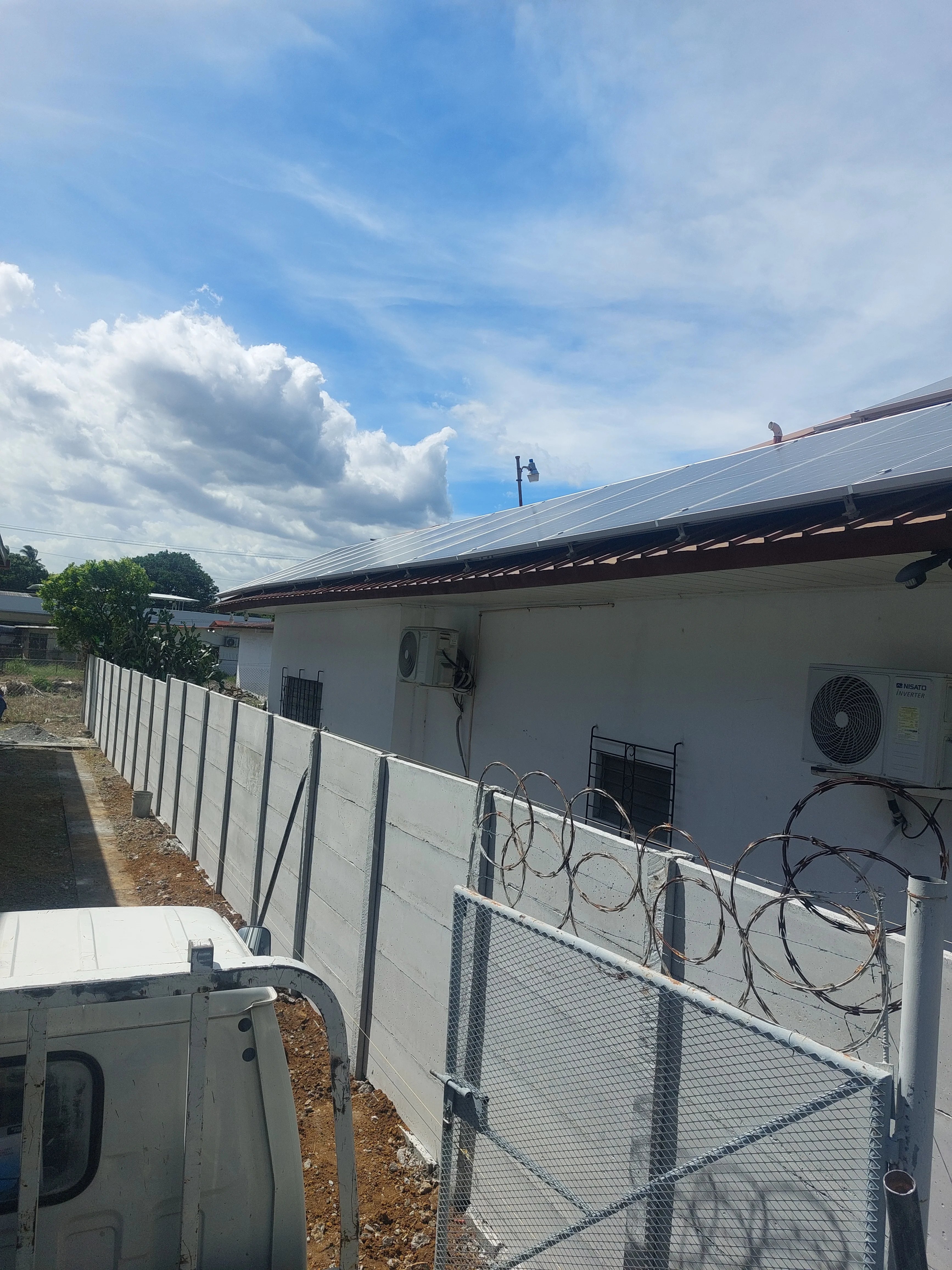 Muro perimetral prefabricado blanco rodeando edificación con paneles solares en zona técnica