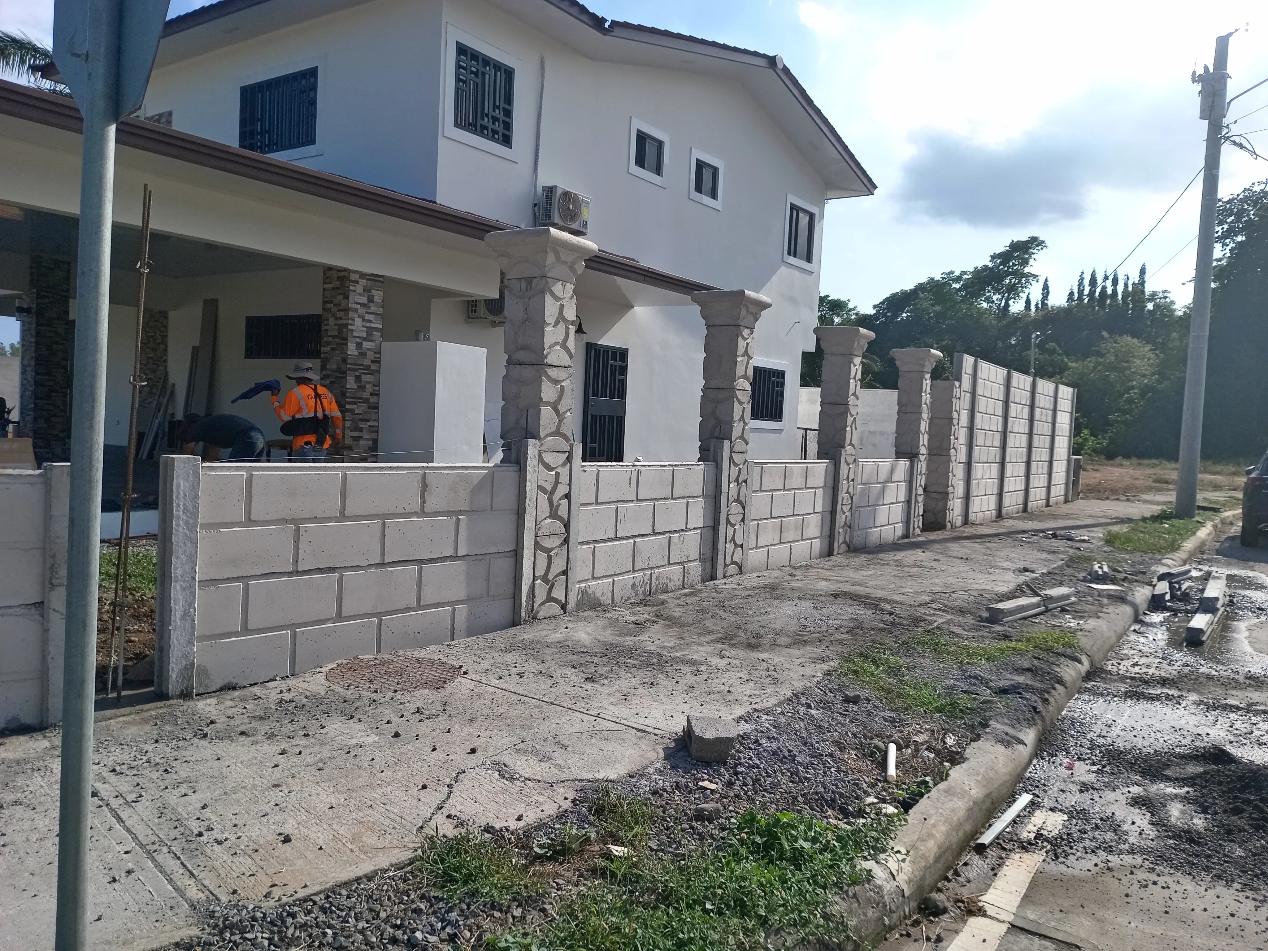 Residencia con muro perimetral bajo y columnas decorativas revestidas en piedra natural