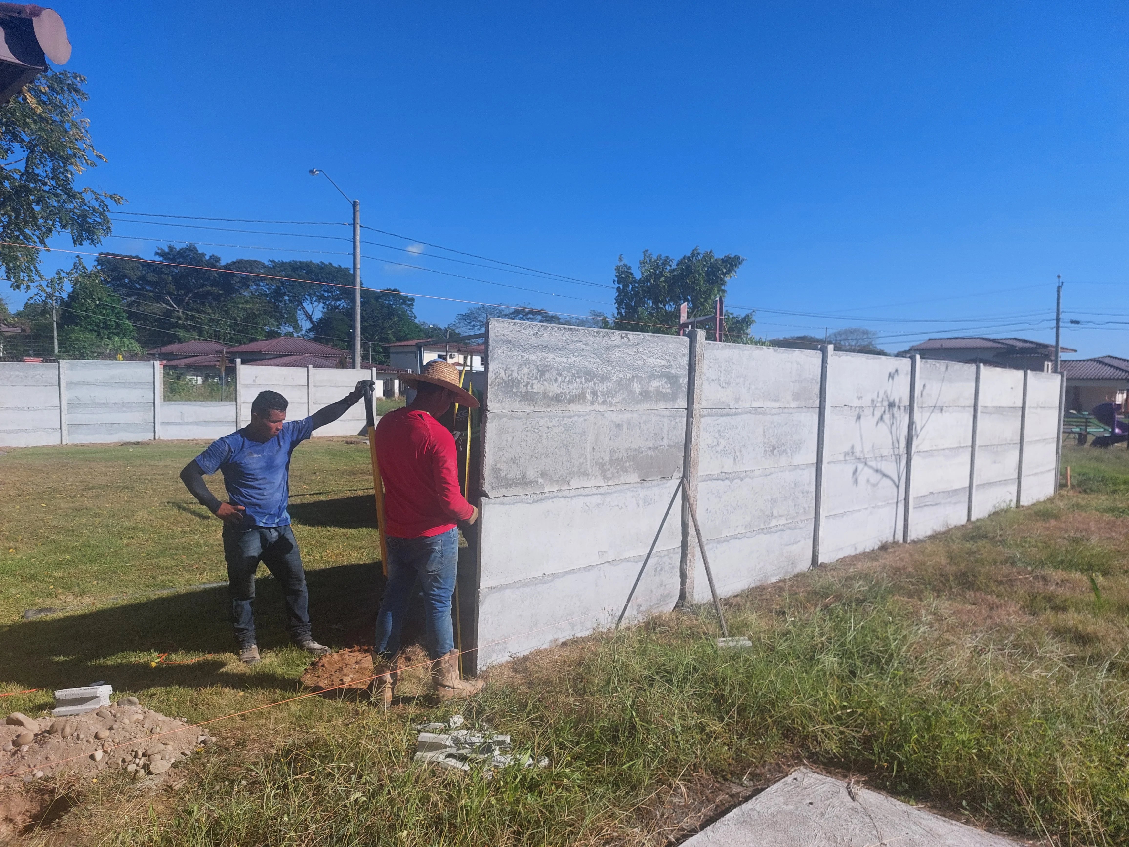 Operarios revisando muro perimetral prefabricado recién instalado en lote residencial de Panamá