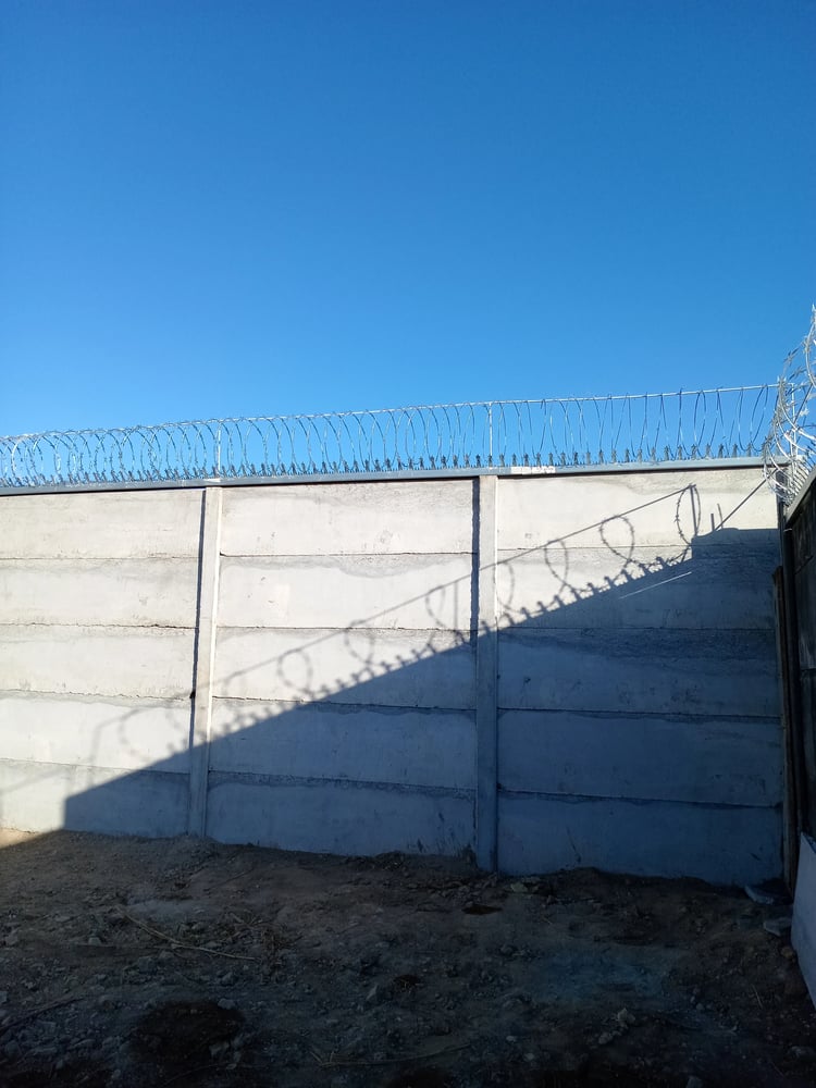 Muro Prefalego FORTEXA de alta seguridad con concertina de alambre de púas en perímetro industrial