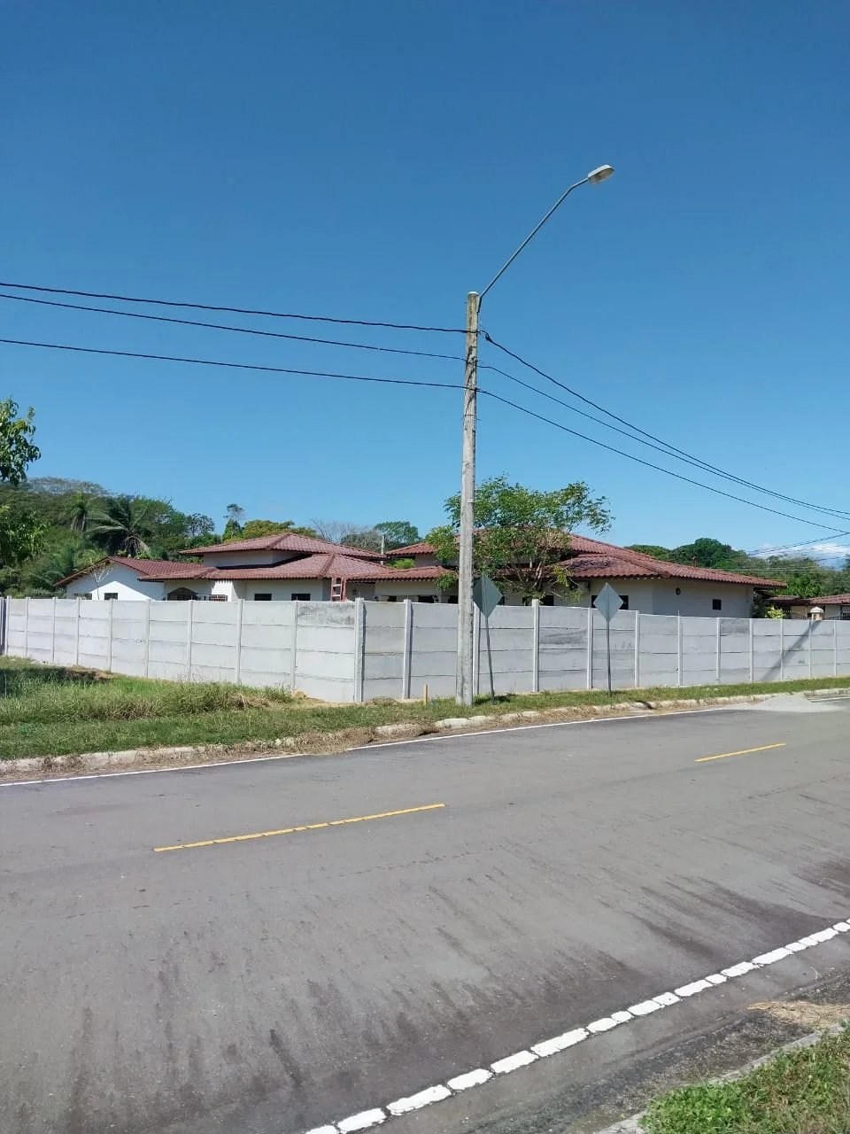 Residencia con techo de teja y muro perimetral prefabricado visto desde la calle del barrio